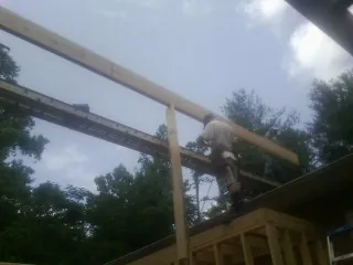 Carpenter setting a ridge beam over a new addition frame — Ice Dam Removal by Roofing Brothers in Rumsey
