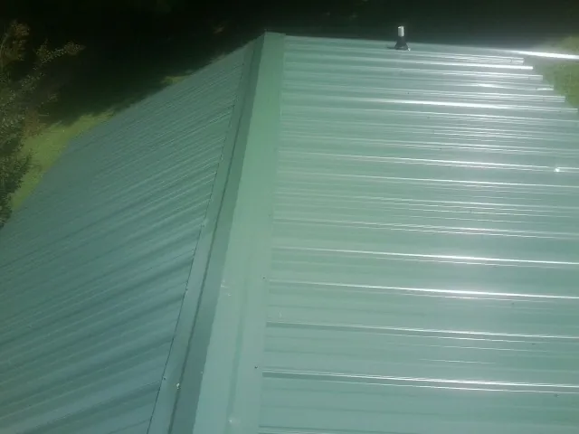 New green metal panels meeting at the ridge of a roof — Flat Roof Repair work by our crew in Rumsey