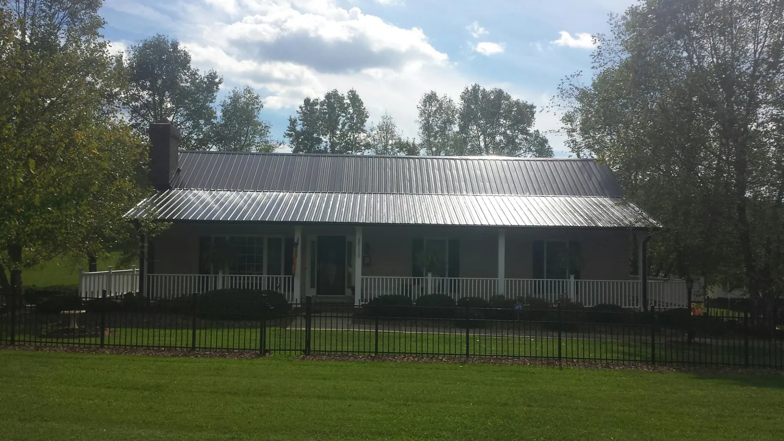 Gray metal roof on a brick ranch with a full width front porch — Gutter Guard Installation work by our crew in Rumsey