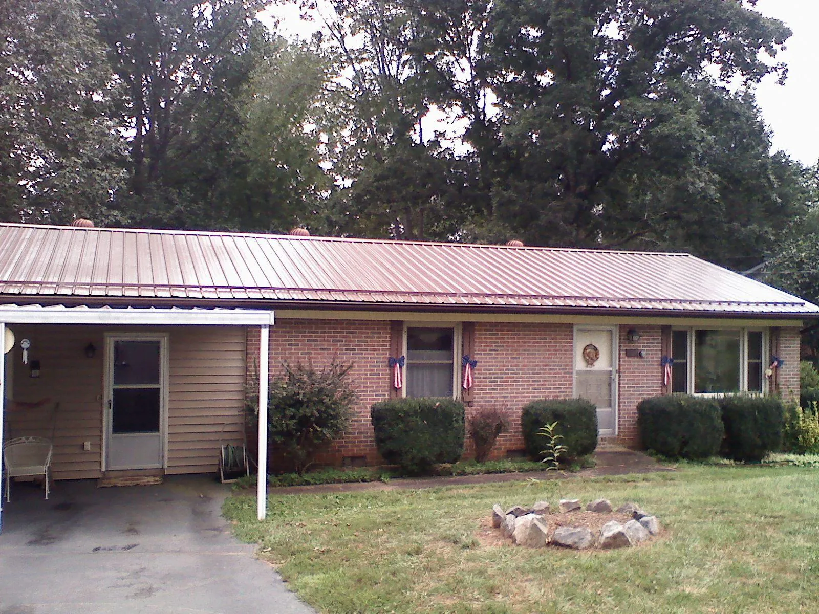 Bronze metal roof and carport on a brick ranch home — Roof Repair work by our crew in Rumsey